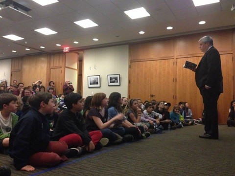 Author Lemony Snicket reads to a group of children seated in front of him in the Stafford Room of the Main Library.